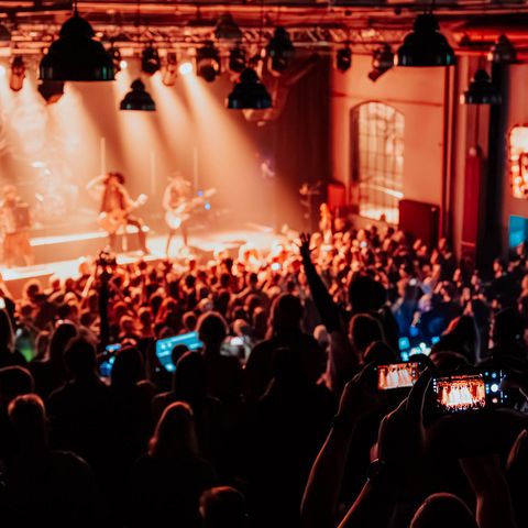 Blick von der Galerie auf ein Konzert im Pumpwerk mit beleuchteter Bühne und Publikum.
